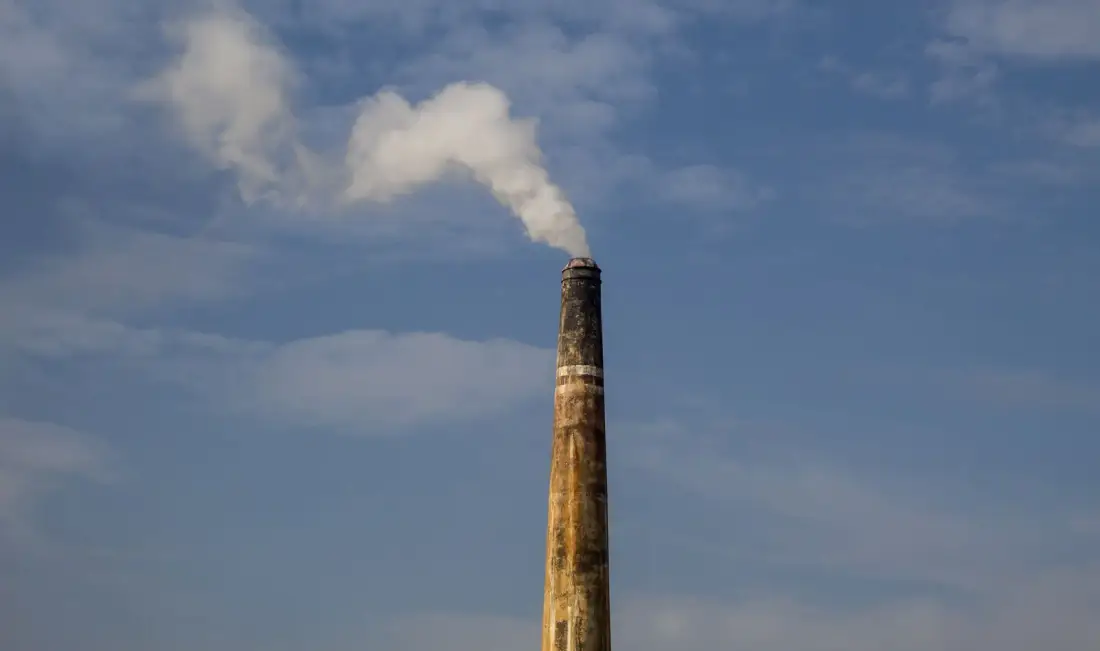 Açık mavi gökyüzüne uzanan endüstriyel fabrika bacası ve baca tahliye sistemi